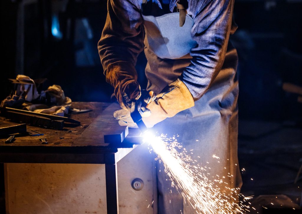 Worker cutting metal with plasma equipment on plant.